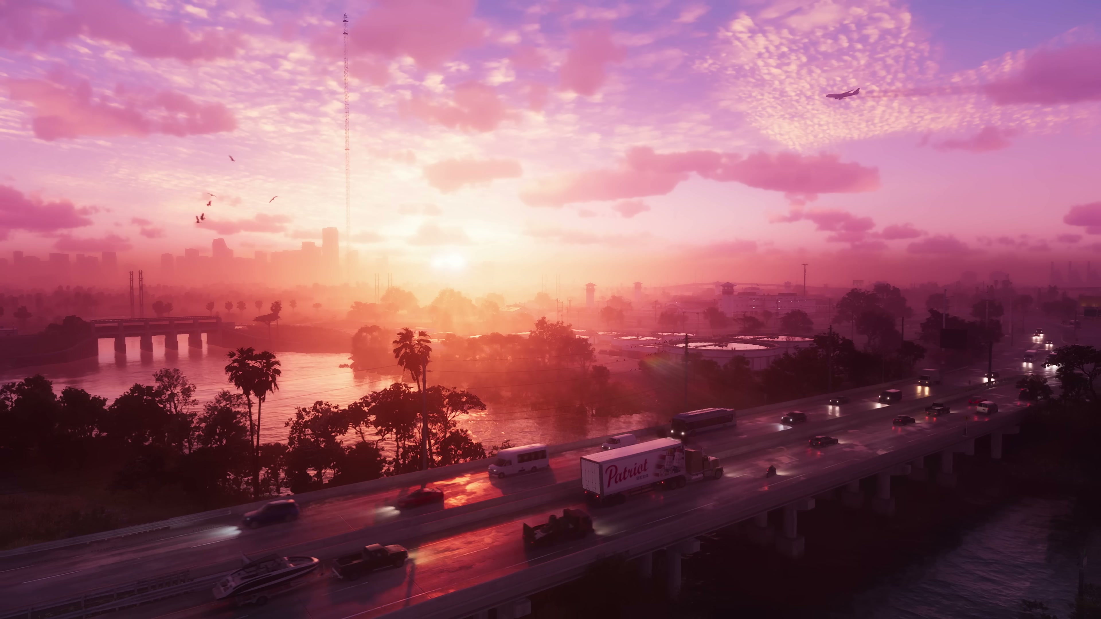 Aerial view of a multi-lane highway crossing water at sunset with a distant city skyline
