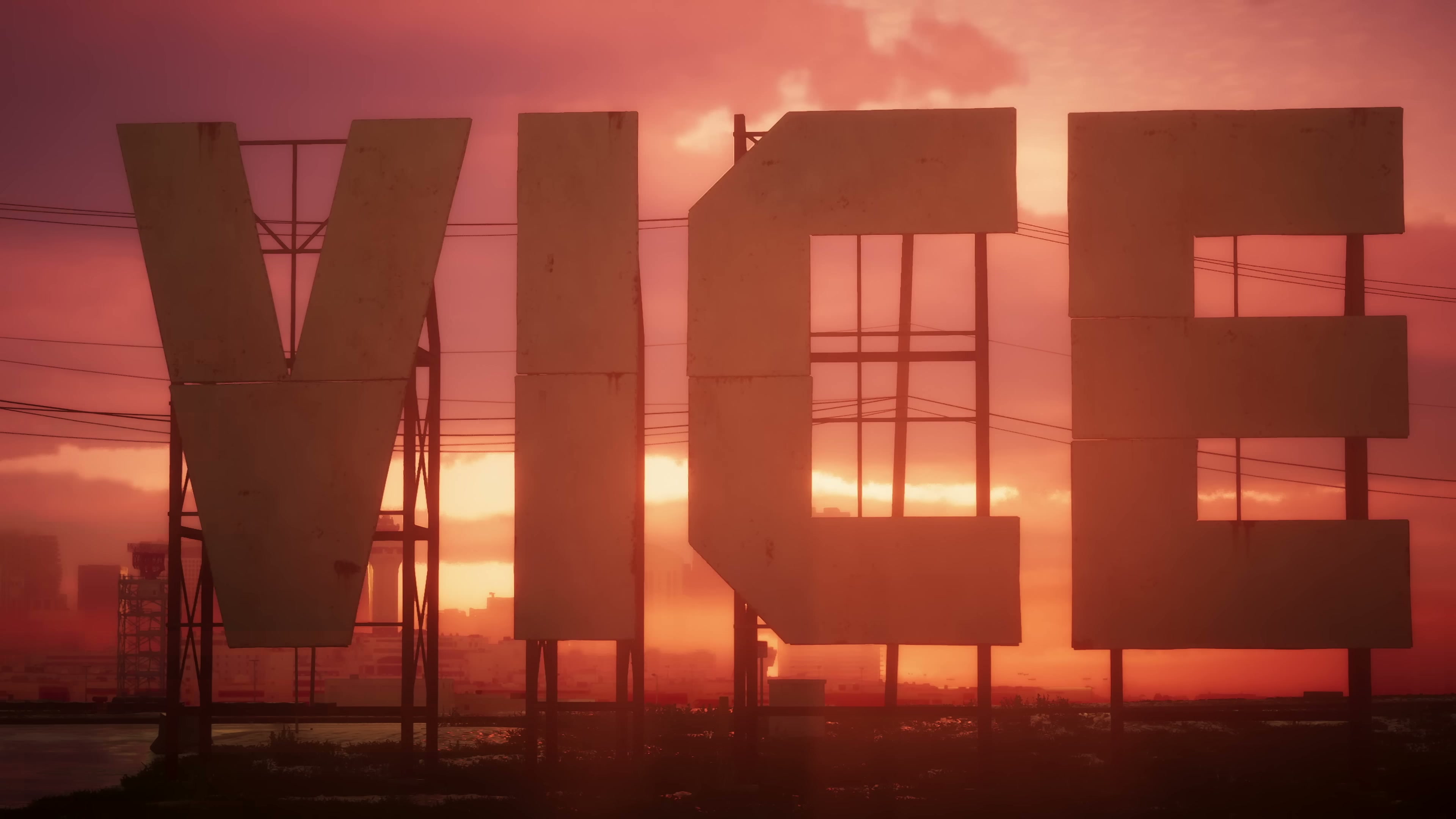 Large freestanding VICE letter signage silhouetted against a red-orange sunset