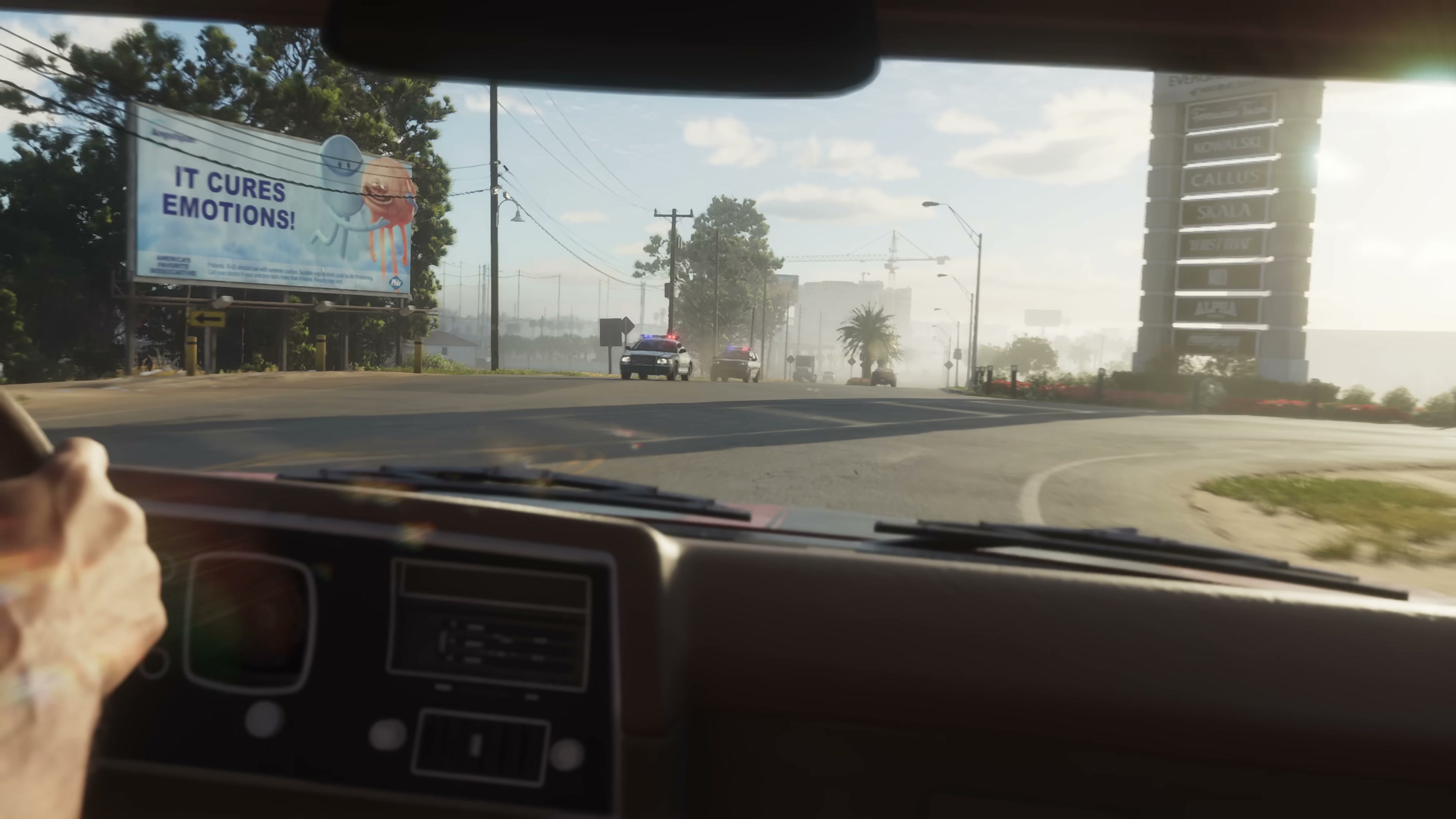 First-person driver's view through a windshield approaching a police vehicle on a sunlit Vice City street