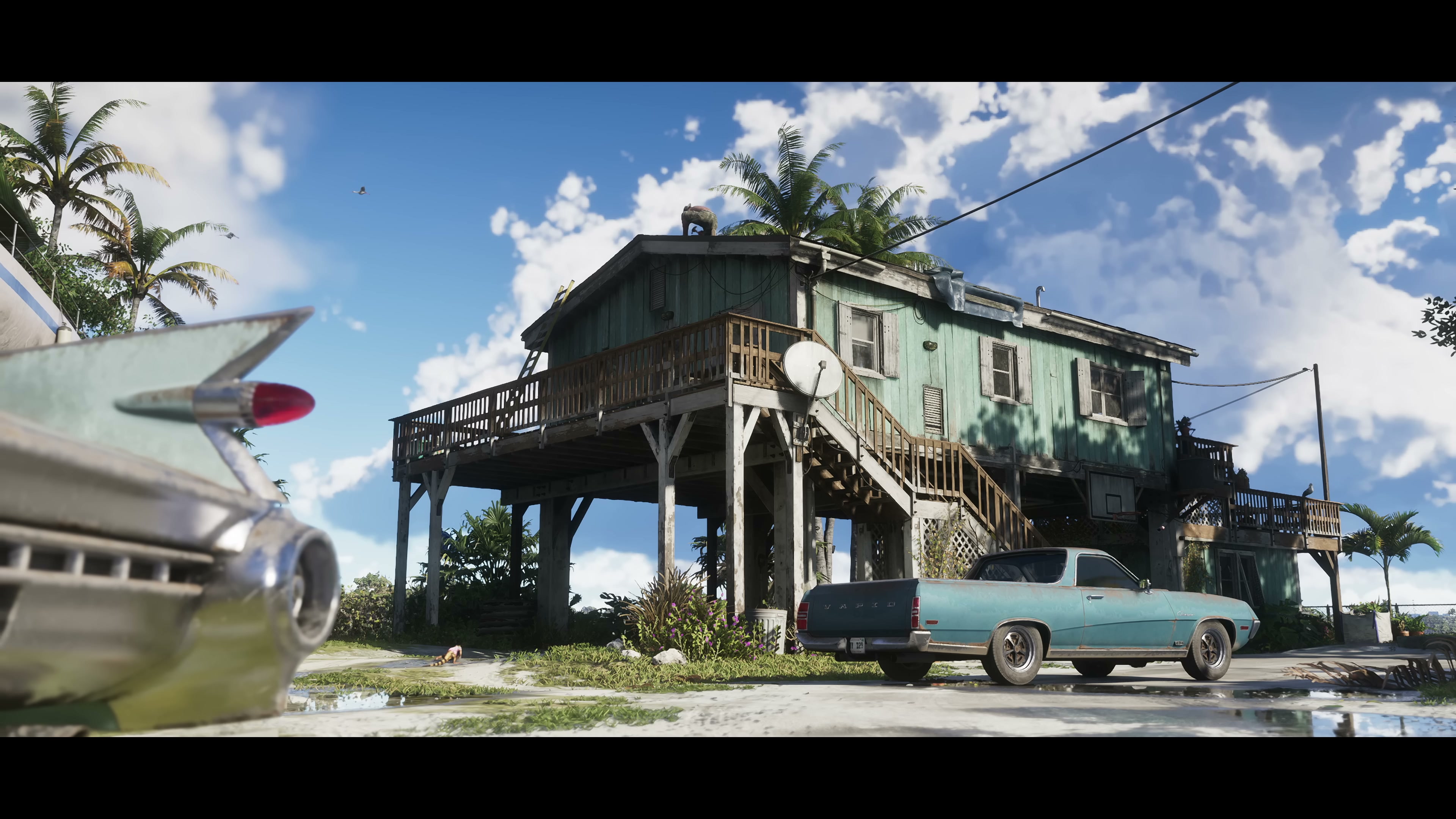 Weathered green stilt house with classic teal convertible parked outside