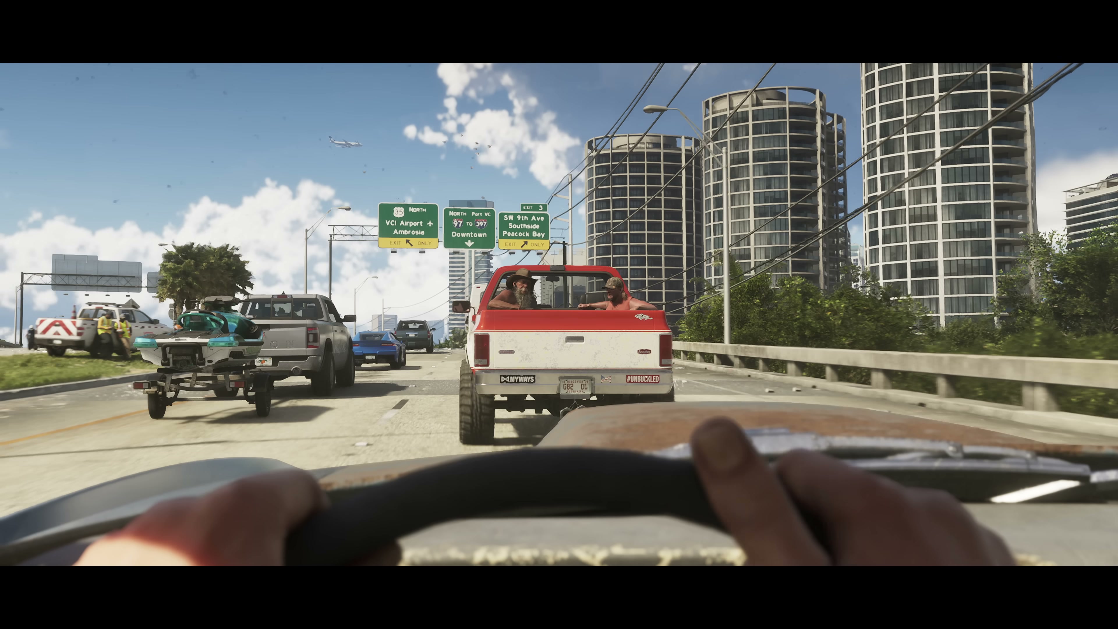 First-person highway view following a red pickup truck past overhead freeway signs reading 'VC! Airport / Ambrosia' and 'Downtown'
